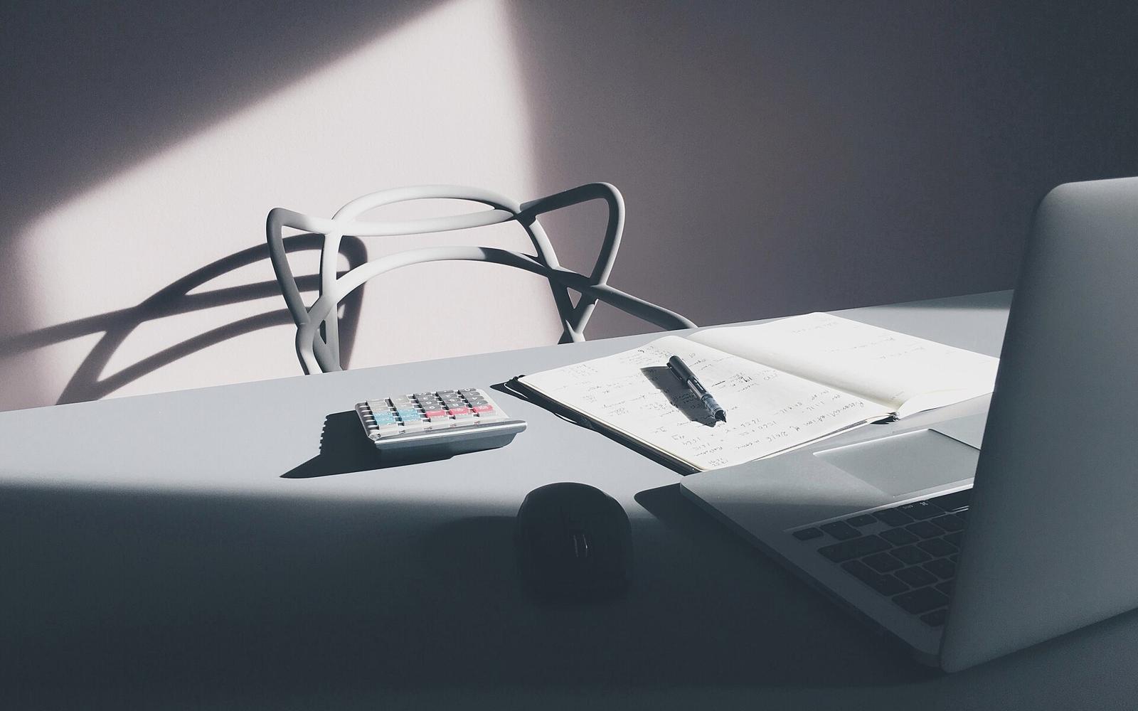 Escritorio con una calculadora, un cuaderno de cuentas y una notebook
